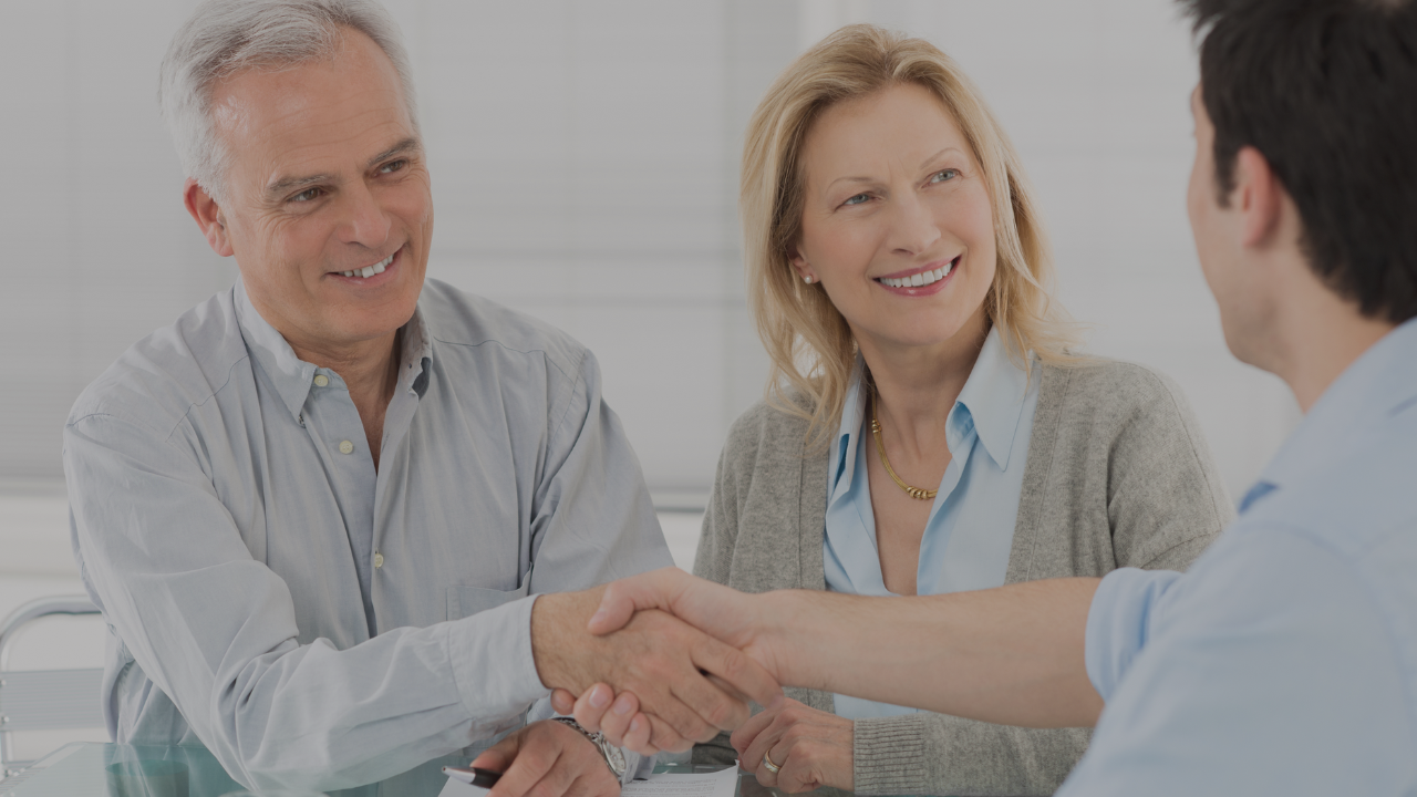 Couple shaking hands with a financial planning advisor